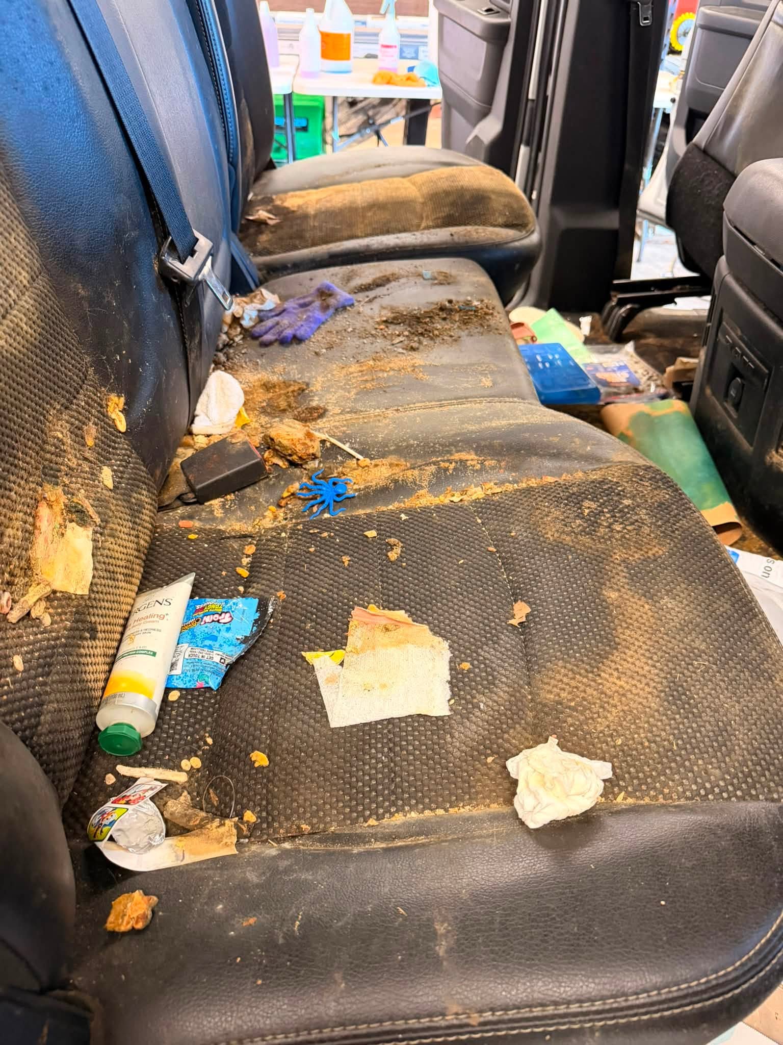Strained rear vehicle seats covered in debris before detailing